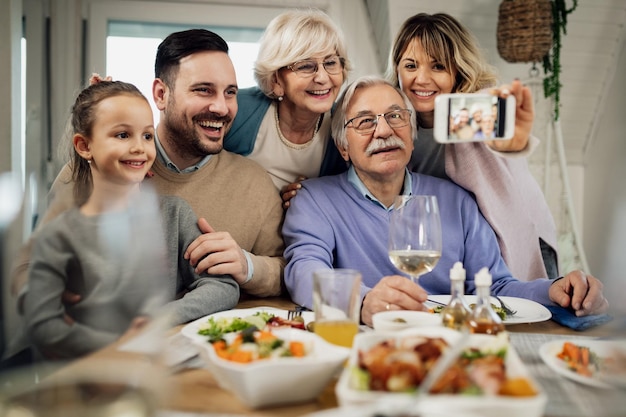 Glückliche Mehrgenerationenfamilie, die Spaß hat, während sie während des Mittagessens im Speisesaal ein Selfie macht