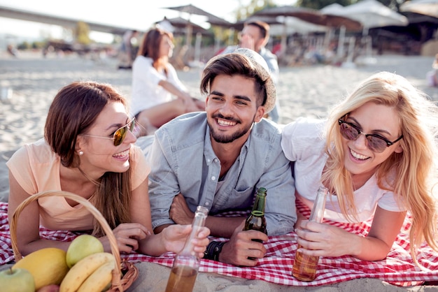 Glückliche Menschen, die Bier am Strand trinken