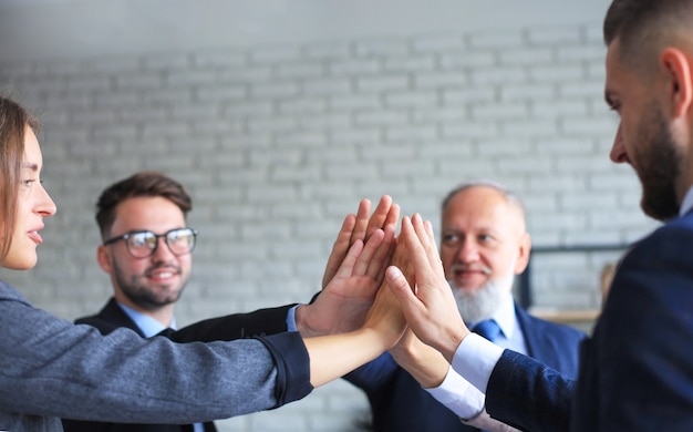 Glückliche Menschen, die im Büro sitzen und ihren Kollegen High Five geben.