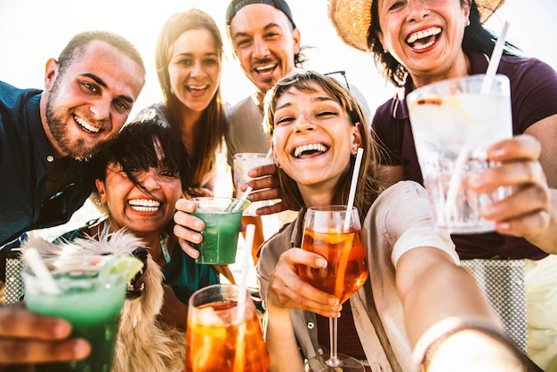 Glückliche Menschen unterschiedlichen Alters, die ein Selfie-Foto machen und draußen Cocktailgläser halten