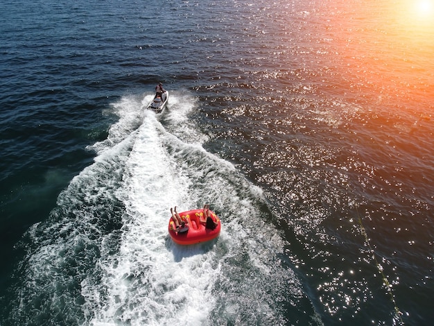 Glückliche Menschen werden auf einer Luftmatratze hinter einem Jetski schwimmen, Touristen fahren das Schlauchboot