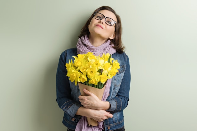 Glückliche mittlere gealterte Frau mit Blumenstrauß der gelben Blumen