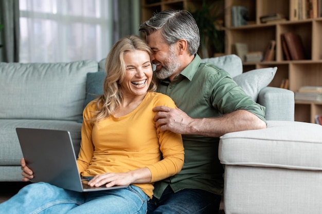 Glückliche Momente Romantische Ehepartner mittleren Alters mit Laptop und Bonding zu Hause