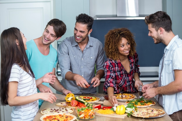 Glückliche multi ethnische Freunde, die zu Hause Pizza zubereiten