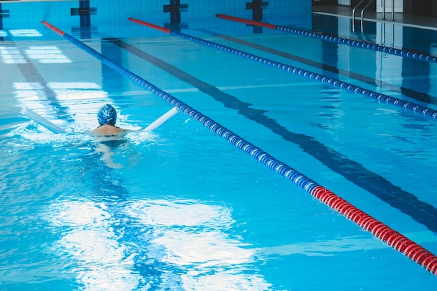 Glückliche muskulöse Schwimmfrau in Schutzbrille und Kappe im Pool und stellt das Konzept von Gesundheit und guter Form dar Schönes weibliches Modell im Wasser beim Synchronschwimmen