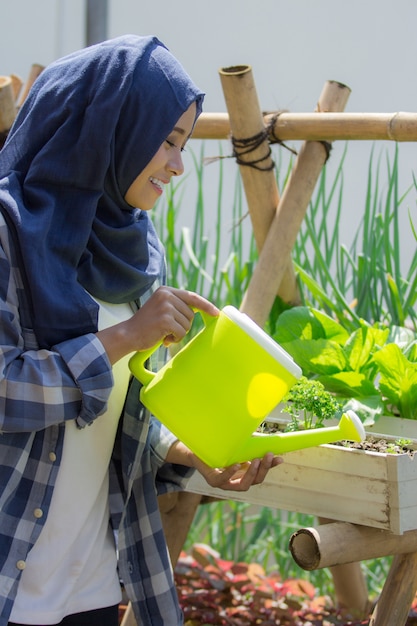 Glückliche muslimische Frau, die ihren Garten wässert