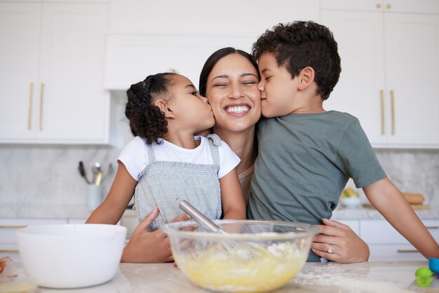 Glückliche Mutter Backen mit niedlichen Sohn und Tochter Bindung Eine junge Frau, die ihren Kindern beibringt, zu Hause zu backen Lächelnde Frau, die Küsse und Zuneigung erhält, während sie mit ihrem Mädchen und ihrem Jungen zu Hause kocht