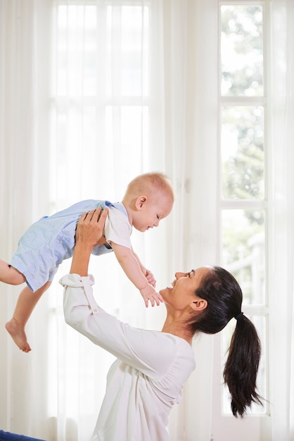 Glückliche Mutter, die Baby hebt