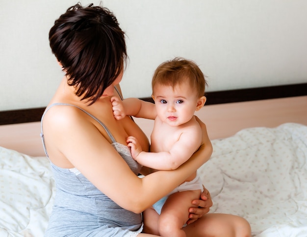 Glückliche Mutter, die ihr Baby hält. Mama küsst ihr Baby