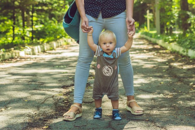 Glückliche Mutter, die im Herbst mit Baby im Park spielt, lächelt Mama an den Händen im Park an?