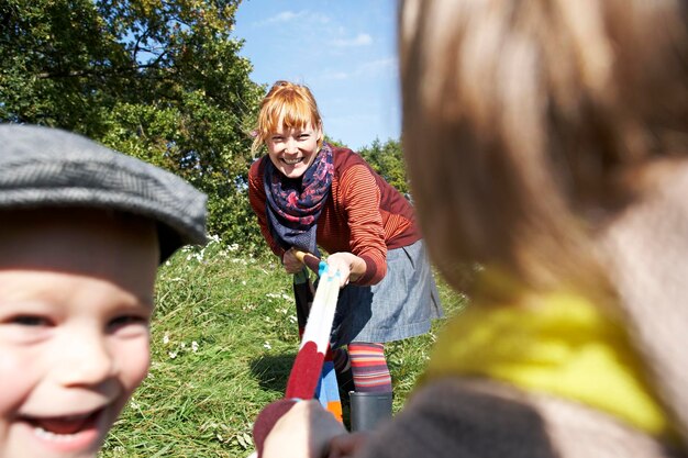 Foto glückliche mutter, die mit kindern auf der wiese spielt