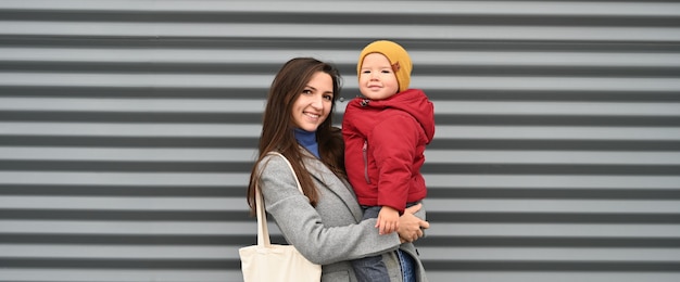 Glückliche Mutter mit ihrem lächelnden Jungen auf einem grauen Hintergrund