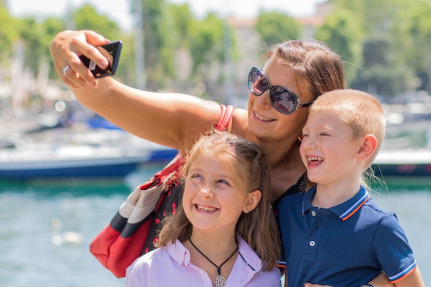 Glückliche Mutter mit ihren Kindern macht an einem sonnigen Tag ein Selfie