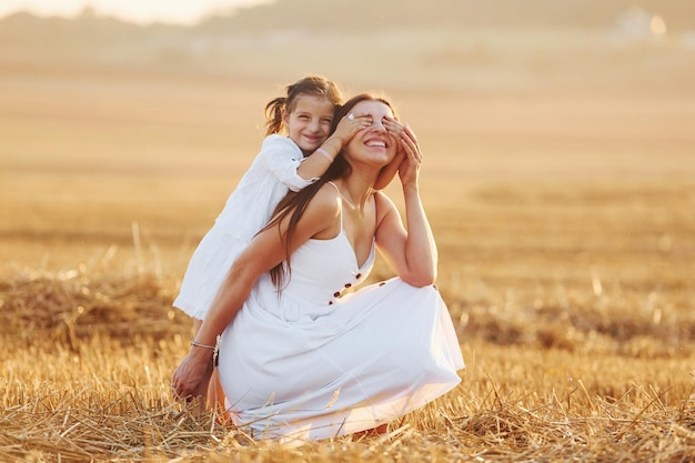 Glückliche Mutter mit ihrer kleinen Tochter, die Zeit zusammen draußen auf dem Feld verbringt