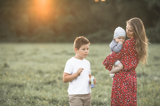 Glückliche Mutter mit Sohn genießt die Natur an einem sonnigen Tag. Aufnahme einer schönen jungen Mutter, die ihren süßen Sohn spielt und umarmt