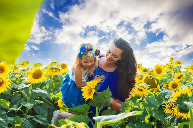 Glückliche Mutter umarmt ihre Tochter in einem Sonnenblumenfeld