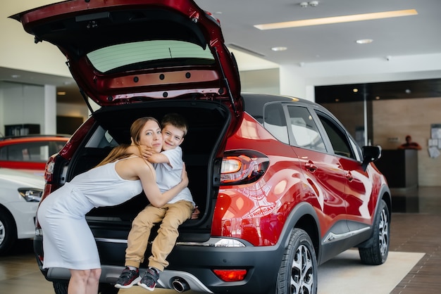 Glückliche Mutter umarmt ihren Sohn, nachdem sie ein neues Auto bei einem Autohaus gekauft hat