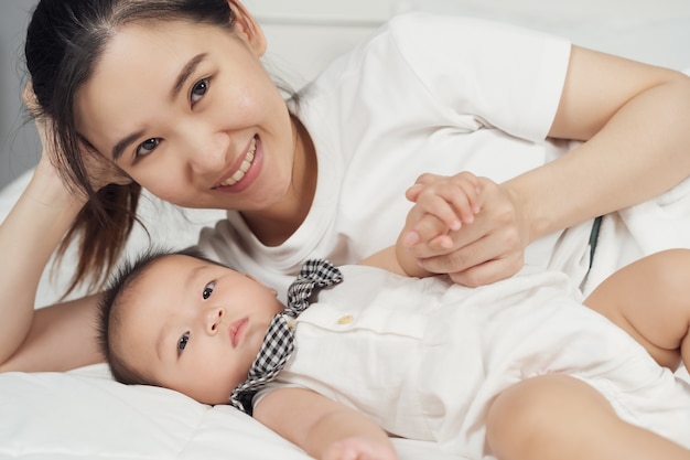 Glückliche Mutter und Baby, die zu Hause auf einem Bett liegen