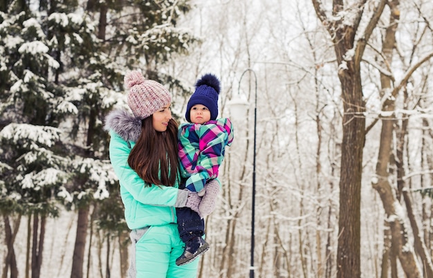 Glückliche Mutter und Baby im Winterpark. Familie im Freien. fröhliche Mama mit ihrem Kind.