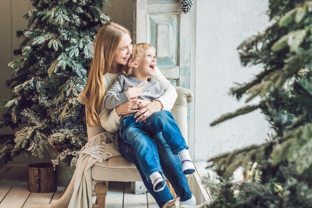 Glückliche Mutter und entzückender Junge feiern Weihnachten. Neujahrsfeiertage