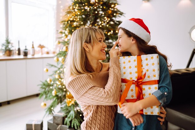 Glückliche Mutter und ihr süßes Tochtermädchen, das Geschenke austauscht Frohe Weihnachten