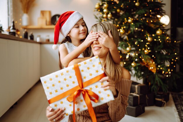 Glückliche Mutter und ihr süßes Tochtermädchen, die Geschenke austauschen. Frohe Weihnachten.