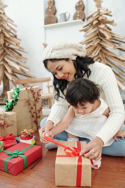 Glückliche Mutter und ihre kleine Tochter, die morgens Weihnachtsgeschenke öffnen