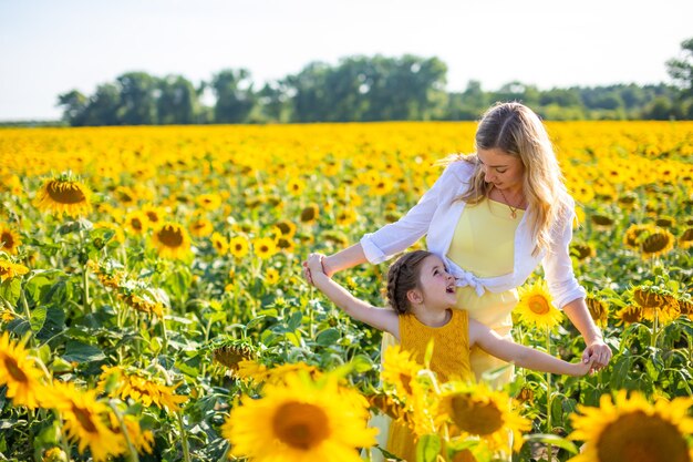 Glückliche Mutter und ihre kleine Tochter im Sonnenblumenfeld