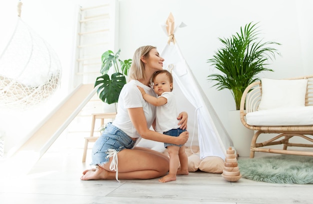 Glückliche Mutter und ihre kleine Tochter zu Hause im Kinderzimmer mit Wigwam Mütterpflege Konzept Zeit zusammen verbringen liebevolle Familie