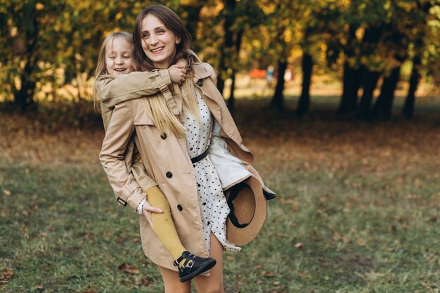 Glückliche Mutter und ihre schöne Tochter haben Spaß und gehen im Herbstpark spazieren.