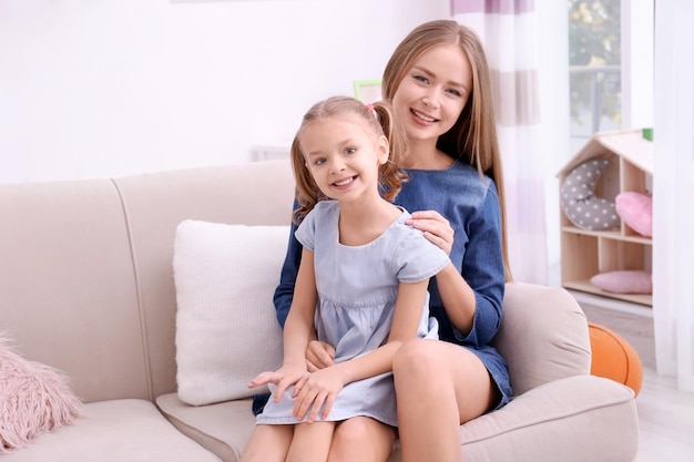 Glückliche Mutter und ihre Tochter auf dem Sofa im Kinderzimmer