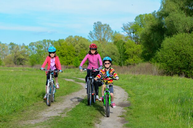 Glückliche Mutter und Kinder auf den Fahrrädern, die draußen, aktiver Familiensport radfahren