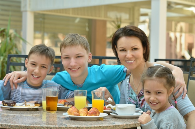 Glückliche Mutter und Kinder beim Frühstück im tropischen Resort