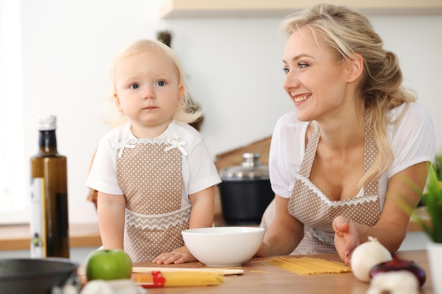 Glückliche Mutter und kleine Tochter, die in der Küche kochen. Zeit miteinander verbringen, Familienspaßkonzept.