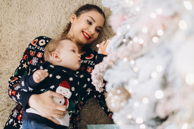 Glückliche Mutter und kleiner Sohn, die an den Weihnachtsfeiertagen zu Hause spielen