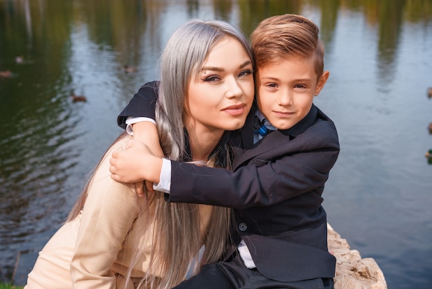 Glückliche Mutter und Sohn, die draußen durch den See umarmt