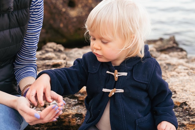 Glückliche Mutter und Sohn, die im Herbst in der Nähe des Meeres an der Küste spielen