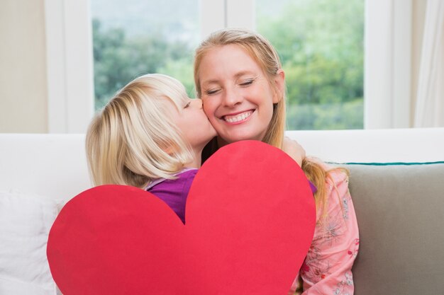 Foto glückliche mutter und tochter auf der couch mit herzkarte