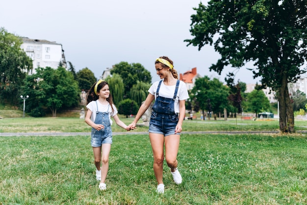 Glückliche Mutter und Tochter, die Hand in Hand hält und im Freien sich schaut. - Konzeptfamilie