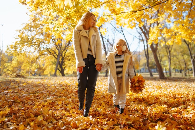 Glückliche Mutter und Tochter haben Spaß im Herbstpark bei Sonnenuntergang. Familie auf Spaziergang. Kindheitsspaziergänge ruhen sich aus