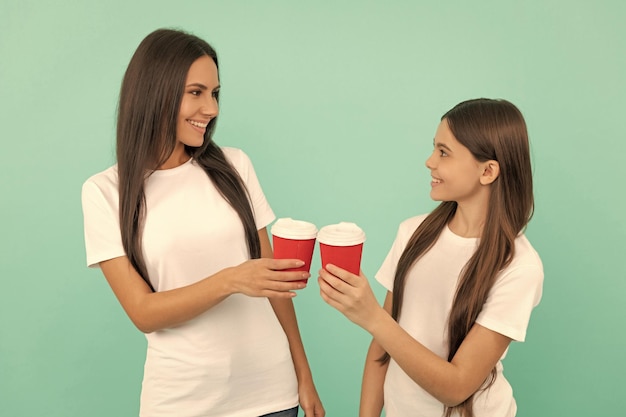 Glückliche Mutter und Tochter halten Kaffee zum Mitnehmen auf blauem Hintergrund