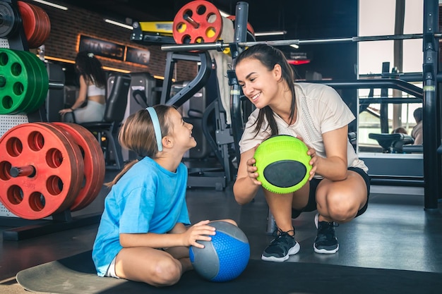 Glückliche Mutter und Tochter im Fitnessstudio mit Bällen