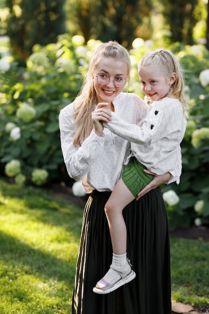 Glückliche Mutter und Tochter im Garten im Sommer für einen Spaziergang