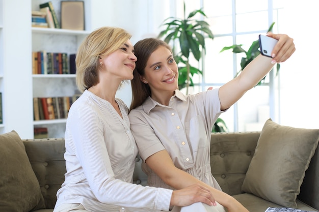 Glückliche Mutter und Tochter mittleren Alters, die zu Hause Selfie machen.