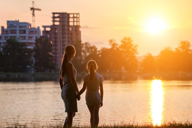 Glückliche Mutter und Tochter stehen zusammen und betrachten Gebäude im Bau, die bei Sonnenuntergang von ihrem zukünftigen Zuhause träumen Familienliebe und Beziehungskonzept