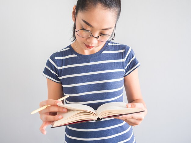 Glückliche nerdy Asiatin liest und studiert ein Buch.