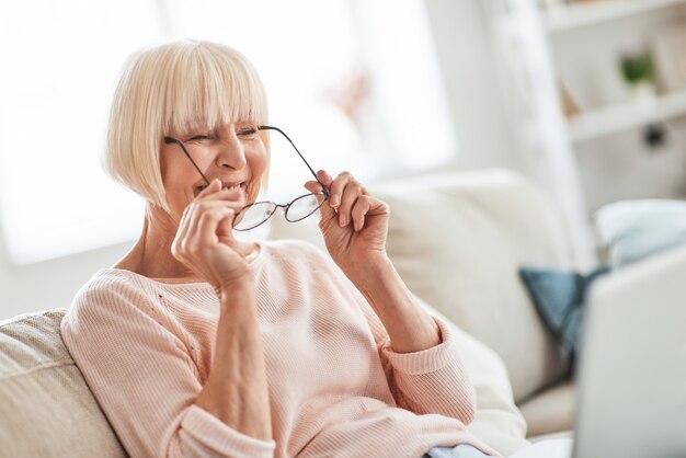 Glückliche Oma. Schöne ältere Frau, die ihre Brille aufsetzt