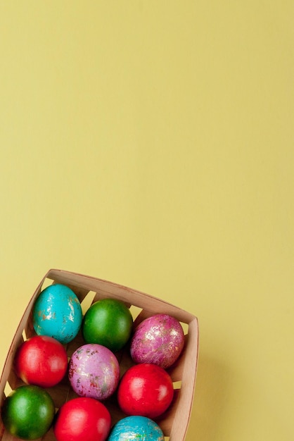 Foto glückliche ostereier mit gelbem hintergrund, goldener glanz, geschmückte eier im korb für grußkarten, werbeplakat, kopierplatz