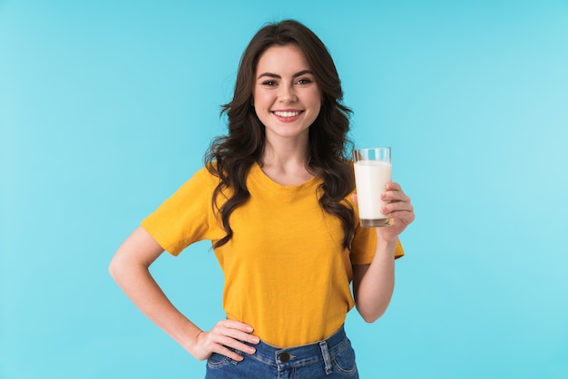 glückliche positive optimistische junge schöne Frau posiert isoliert über blauer Wand mit Milch.