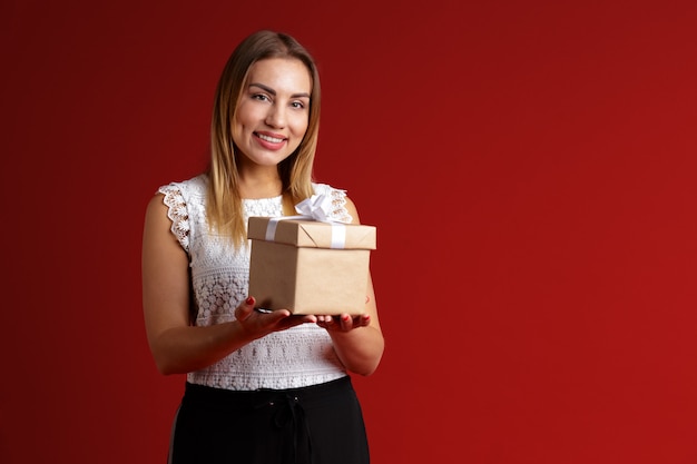 Glückliche recht junge Frau, die Geschenkbox hält